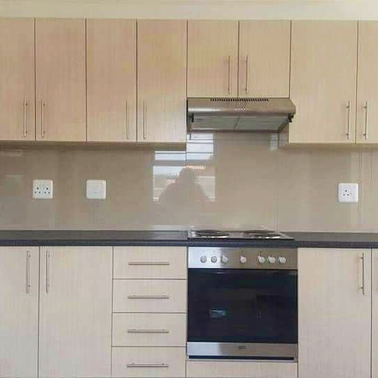 Cream tiled kitchen with white cabinets and oven for affordable housing in Paarl