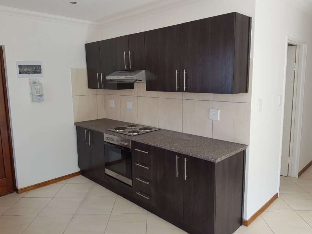 Side kitchen view with dark cabinets and stove for affordable housing in Paarl